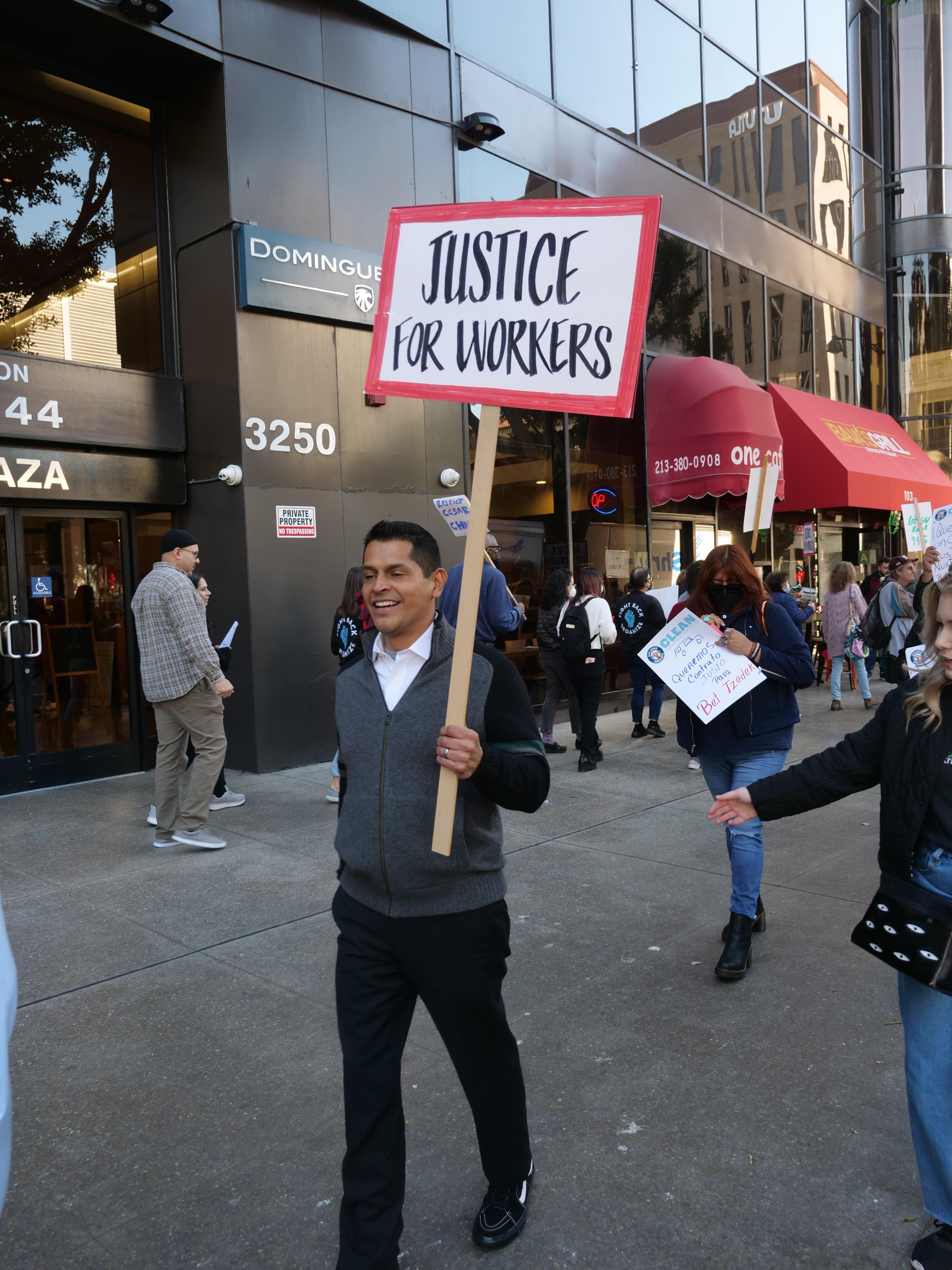 California State Assemblymember Miguel Santiago holds picket sign that says Justice for Workers